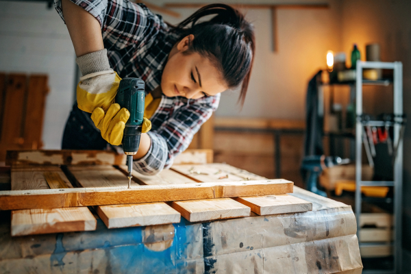 Woman using power drill on a piece of wood